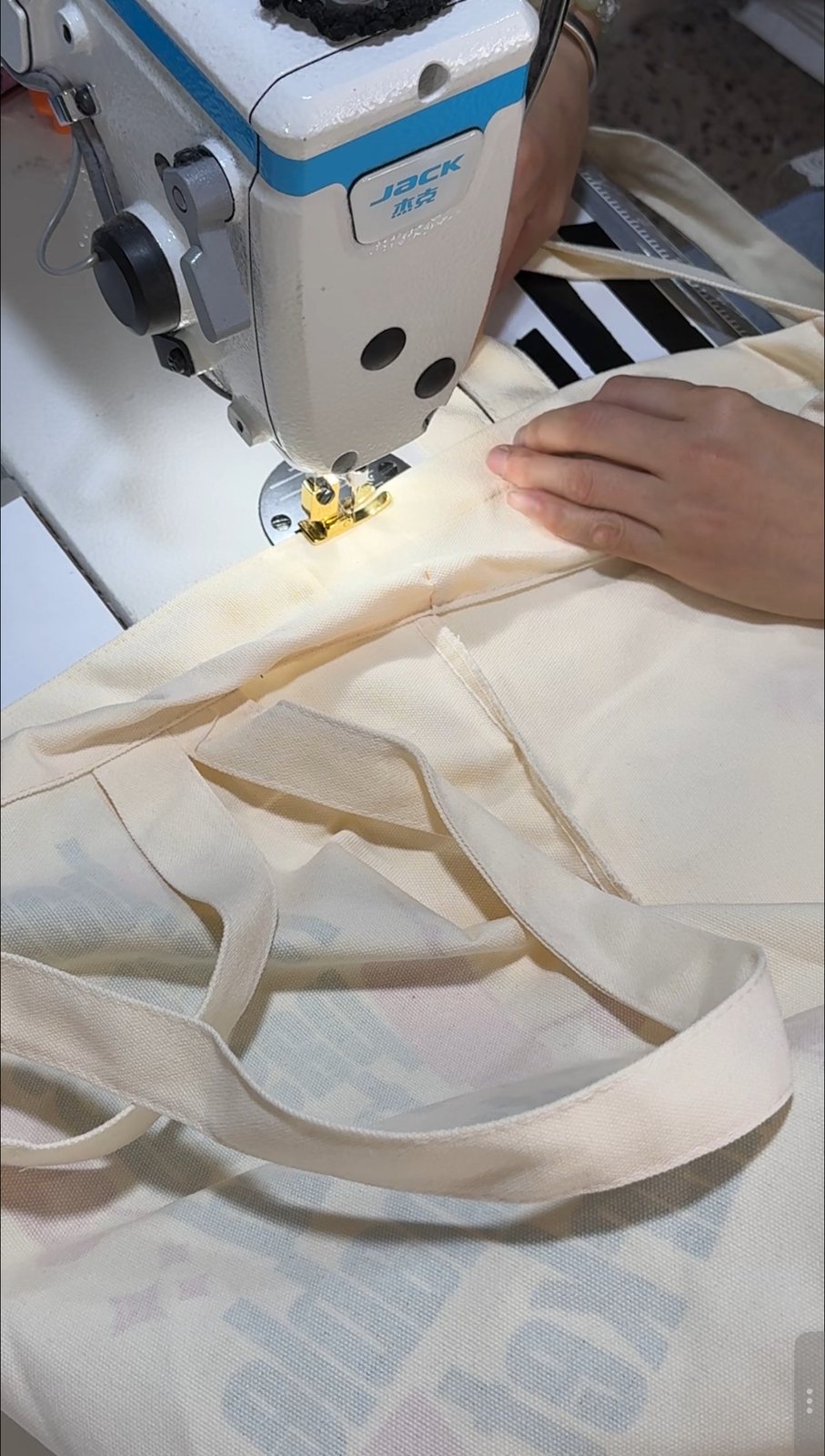 Sewing handles on a natural canvas tote bag